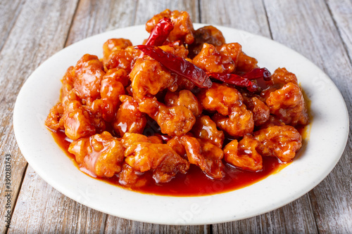 A view of a plate of spicy orange chicken, in a restaurant or kitchen setting.