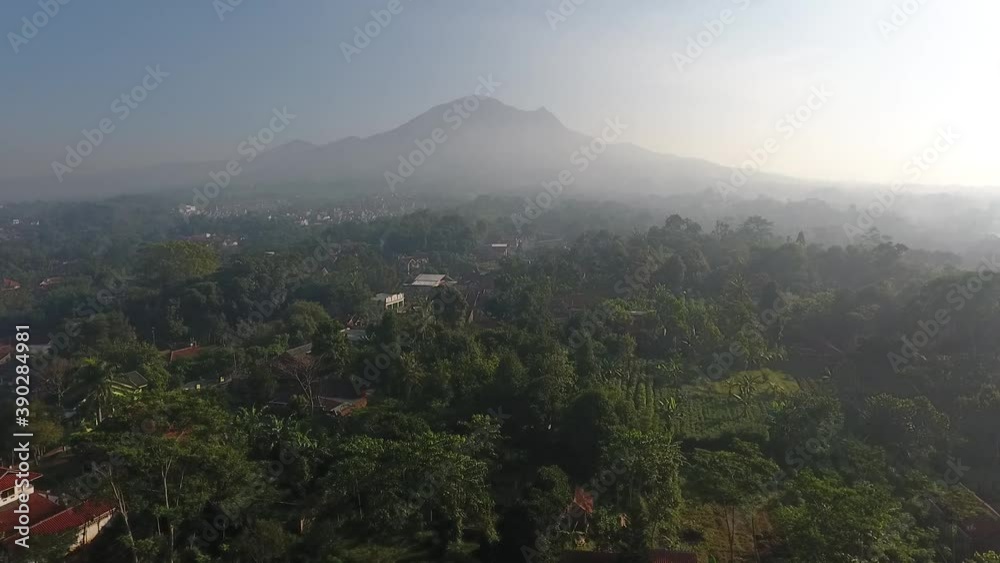 A beautiful and serene green village with high trees nearby the mountain in Indonesia A beautiful and serene green village with high trees nearby the mountain in Indonesia
