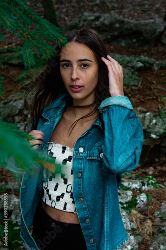 Vertical shot of a young beautiful Caucasian woman in the forest photo