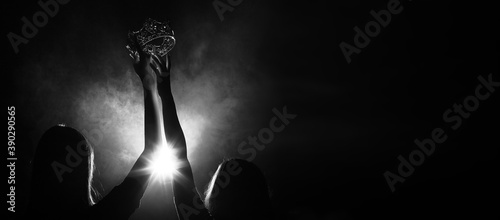 Silhouette abstract of two hands try to reach Diamond Crown as Miss Beauty Queen Pageant Contest as final competition, finale winner moment. Backlit smoke low exposure dark background copy space photo