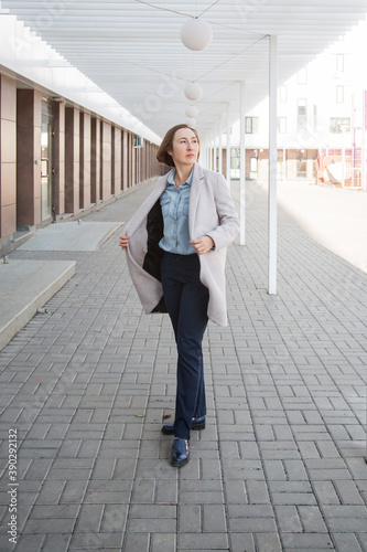 business woman in the beige coat stand in the autumn city