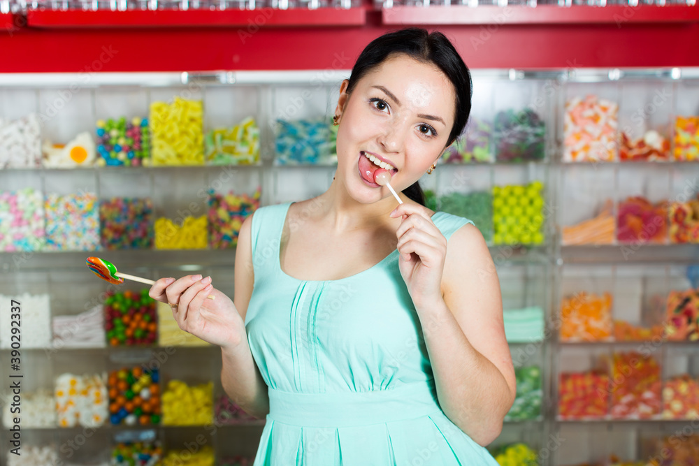 Young woman sucking lolly in candies shop