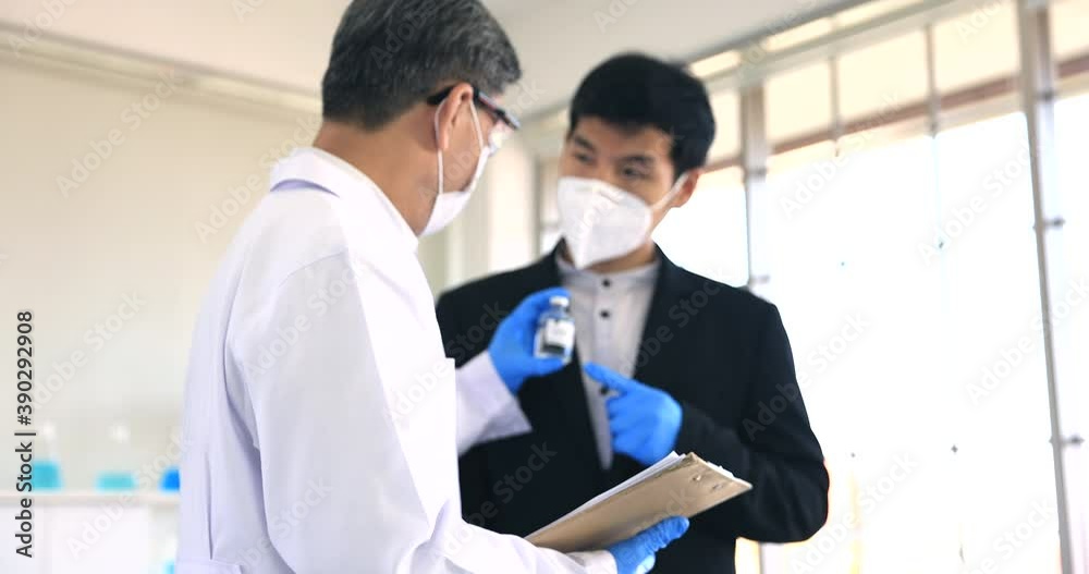 Asian doctor and businessman holding the COVID vaccine on laboratory after test on human success and have agreed to buy and sell. Asian doctor and businessman holding the COVID vaccine on laboratory after test on human success and have agreed to buy and sell.