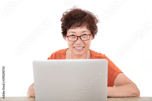 Фотография Old Chinese lady wearing glasses sitting in front of a laptop in front of a whit