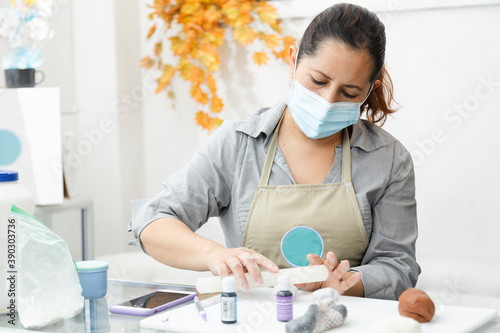 Fotografi Pastry chef working with fondant to decorate a cake - Woman cooking with mask -