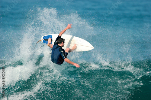 A surfer boosts a radical aerial move on a wave in the ocean. Slight motion blur.