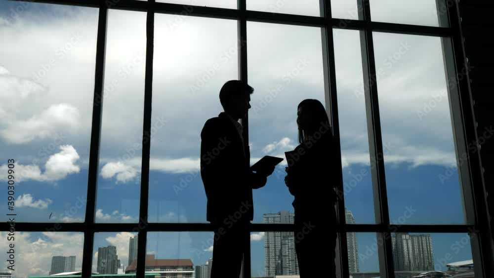Silhouettes of two business people discussing in the office. Silhouettes of two business people discussing in the office.