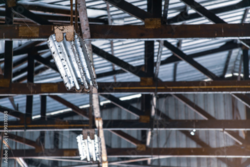 The selected focus of Old Fluorescent lights with cobwebs rust hanging from the metal structure in the factory. And Safety Dangerous Electronic waste Concept