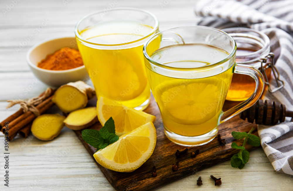 Energy tonic drink with turmeric, ginger, lemon and honey on a white wooden background