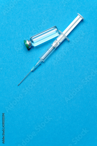 Syringe and ampoules with medicines or vaccine over blue background