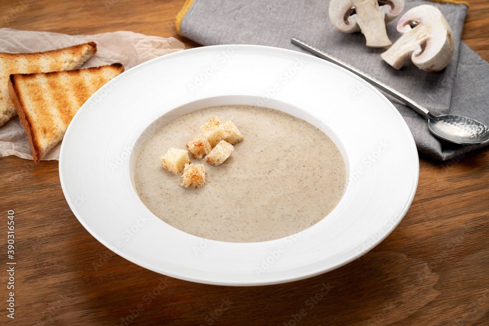 Mushroom soup puree with croutons and mushrooms on a wooden table Mushroom soup puree with croutons and mushrooms on a wooden table