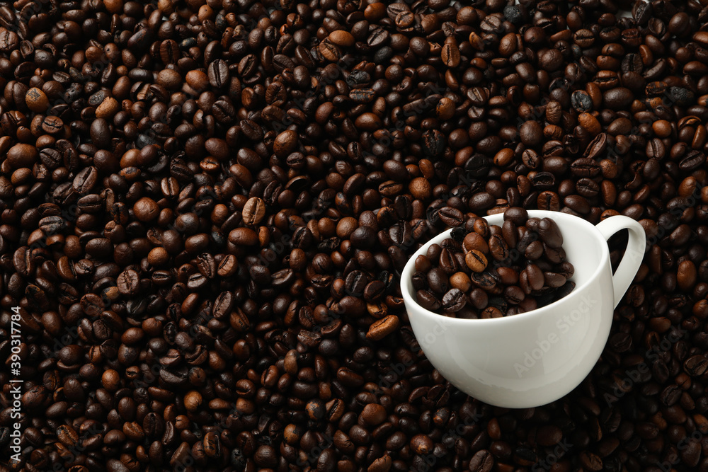 Fototapeta premium White cup on coffee beans background, space for text
