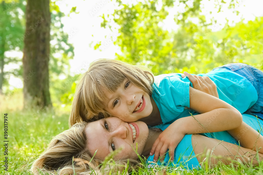 child with mother play outdoors in a park on the mother in the grass child with mother play outdoors in a park on the mother in the grass