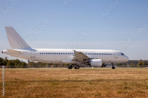 A white plane on the airport runway is taxiing. Takeoff and landing. Arrival and departure. Place for text. Passenger plane isolated mockup. Airplane landing. Travel by air transport. Copy space.