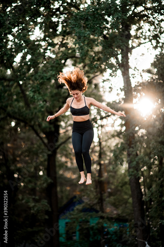 beautiful woman bouncing on trampoline and performs trick in the air