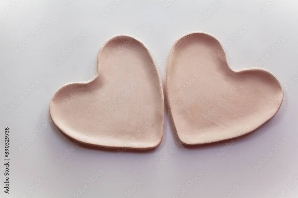 Obraz premium Two heart plates made of fireclay on a white background. Creation of ceramics. Bisquit firing ceramics.