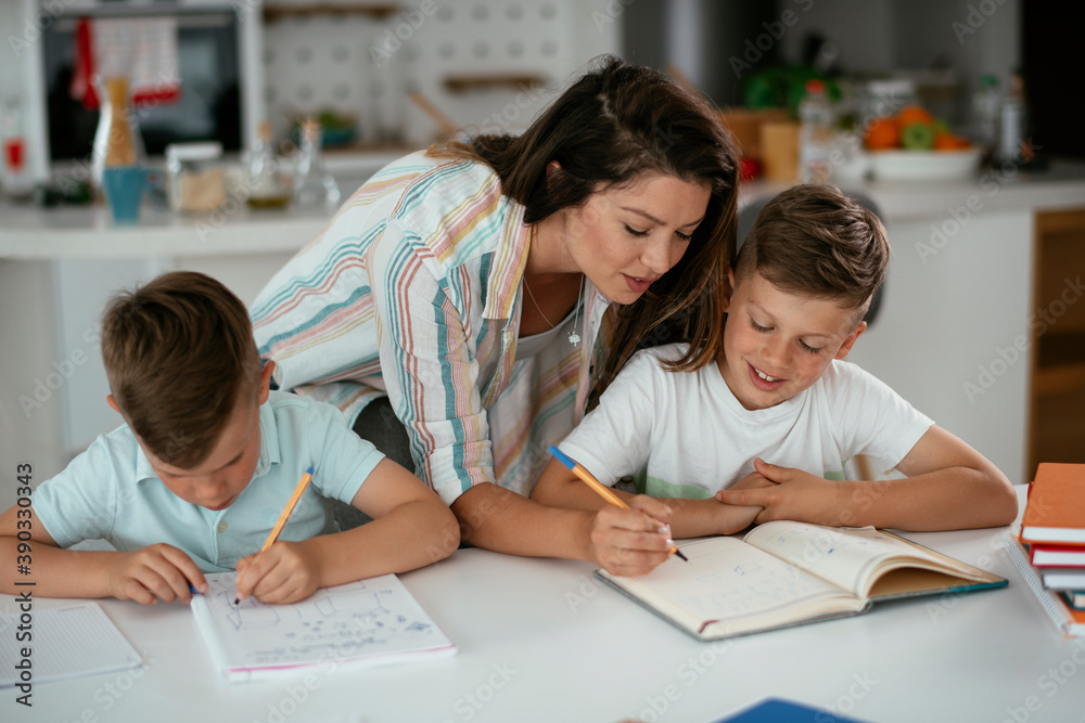 Mother helping her son with homework at home. Little boy learning at home.. Mother helping her son with homework at home. Little boy learning at home..