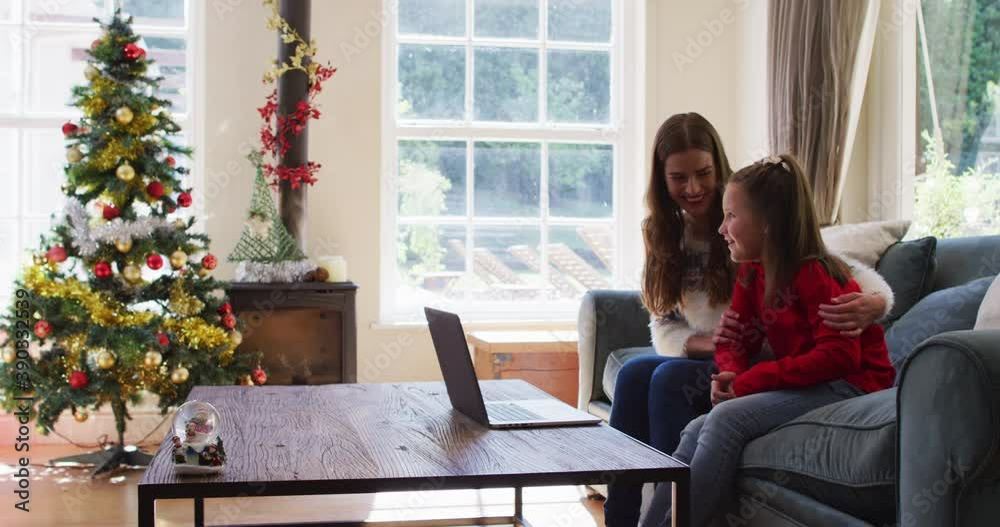 Caucasian mother and daughter smiling and waving while having a video call on laptop sitting on the Caucasian mother and daughter smiling and waving while having a video call on laptop sitting on the