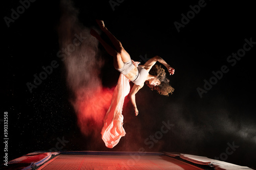 sporty young woman jumping on trampoline and doing flip tricks in the air.