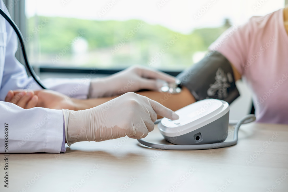 Fototapeta premium Doctor evaluates the patient with a stethoscope, blood pressure monitor and records the results, health medical checkup concept