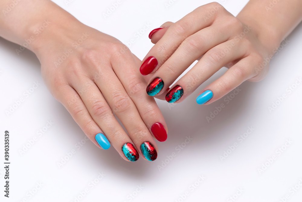 Red, blue manicure with shimmery foil on short oval nails close-up on a white background Red, blue manicure with shimmery foil on short oval nails close-up on a white background