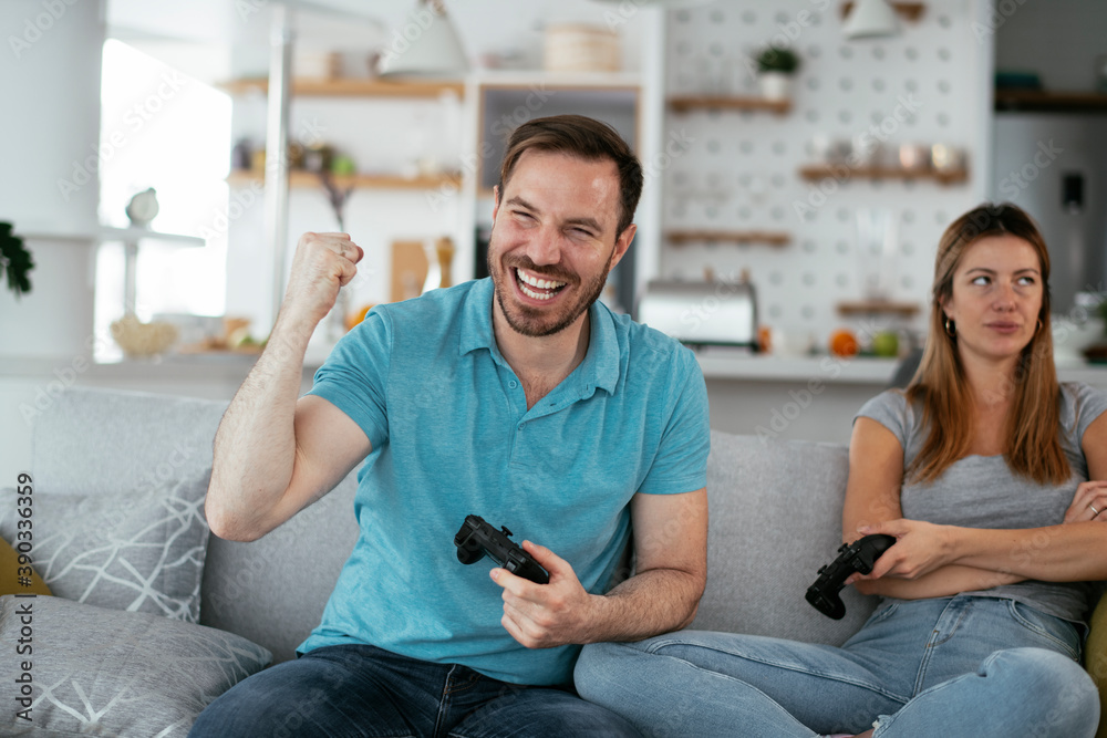 Husband and wife playing video game with joysticks in living room. Loving couple are playing video games at home Husband and wife playing video game with joysticks in living room. Loving couple are playing video games at home