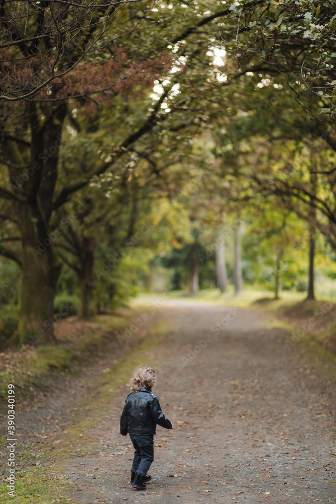 Happy little girl in leather jacket walking in the autumn forest. Smile and have fun Happy little girl in leather jacket walking in the autumn forest. Smile and have fun