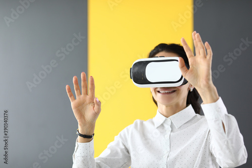 Woman stands in virtual reality glasses and holds her hands up. Fun and games for adults and children concept