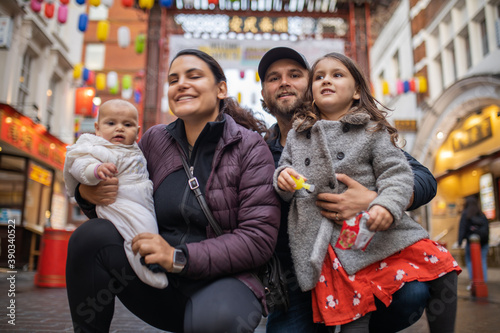 Two happy parents and their two daughters posing in a blurry Chinatown alley