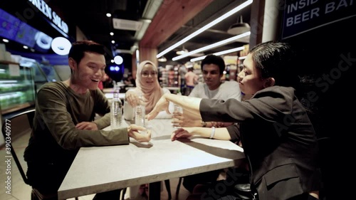 a group of asian friends seating and chatting indoor at food court