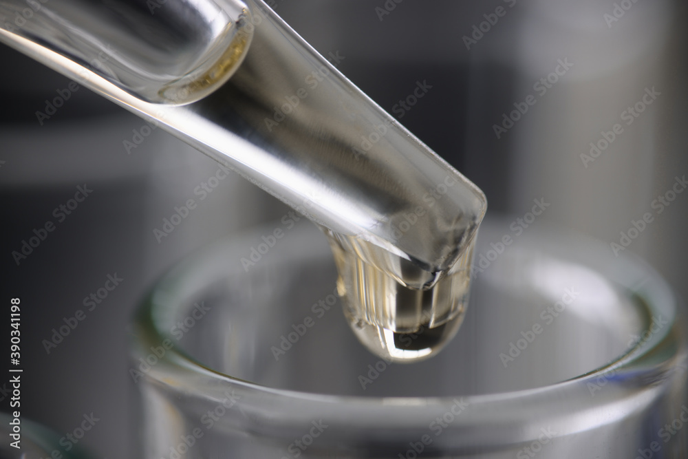 Drop of clear liquid drips into test tube on measuring tube. The benefits of water in every drop concept Drop of clear liquid drips into test tube on measuring tube. The benefits of water in every drop concept