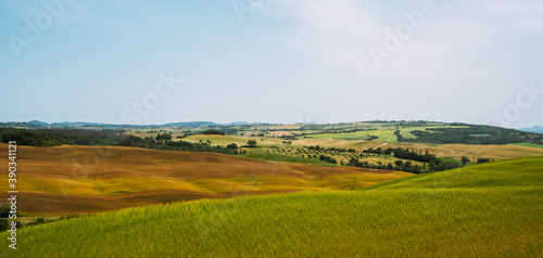 Tuscany village landscape on a sun day, Italy. Beautiful green hils and rural fields. Agricultural area with fields and cypresses.