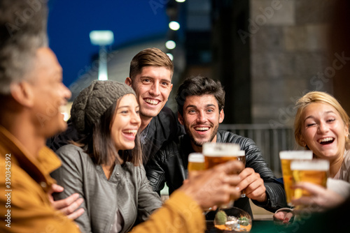 group of friends toasting with beers, people of different culture and ethnicity in happy moments of social gathering, focus on the two boys, concept of happy and carefree youth
