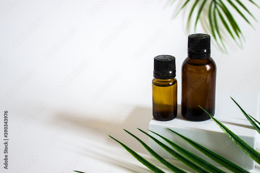 glass brown jars with plant stracts and oils on a light white background. For cosmetics or cosmetology background. stand for advertising beauty products. Plants decor eucalyptus, fern, spruce