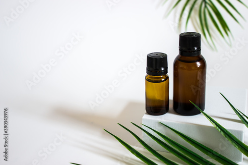 glass brown jars with plant stracts and oils on a light white background. For cosmetics or cosmetology background. stand for advertising beauty products. Plants decor eucalyptus, fern, spruce