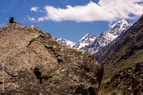 Snow capped Himalayan mountains rising beyond a large rocky boulder capped with a small Buddhist stone stupa.