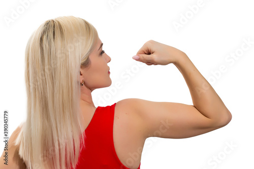 Athletic woman pumping up muscles on gray background