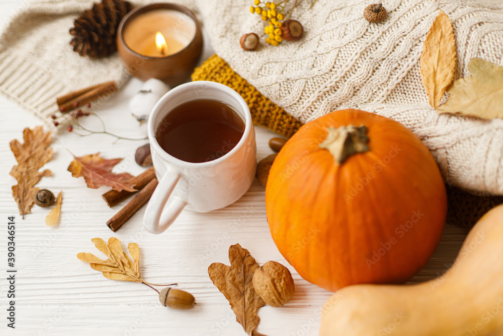 Warm tea, pumpkins and spices on background of cozy knitted sweaters, autumn leaves and candle Warm tea, pumpkins and spices on background of cozy knitted sweaters, autumn leaves and candle