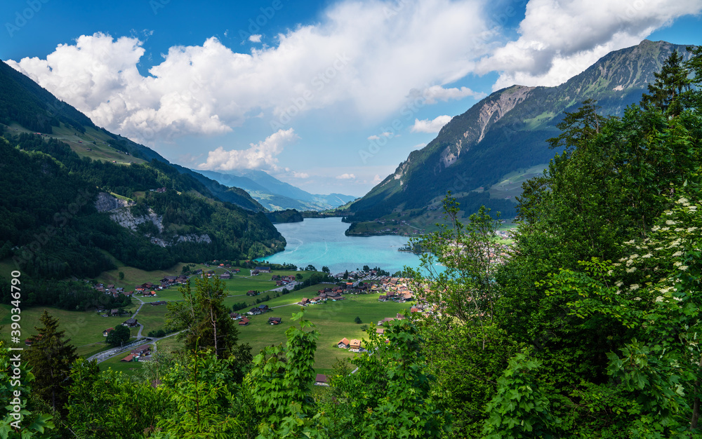 Panoramic view of idyllic scenery of Lake Lungern with fresh green meadows. Beautiful sunny day in springtime in Switzerland. Summer rural view. Village in green mountain valley.