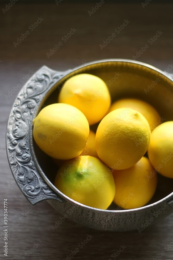 Fresh lemons in vintage silver bowl. Selective focus.
