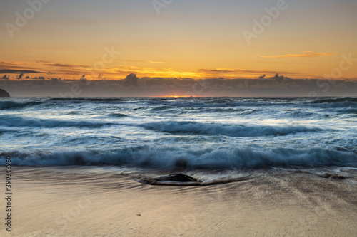 Sunrise seascape with light cloud, waves and rocks