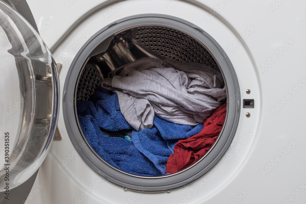 Open door in washing machine with laundry inside.