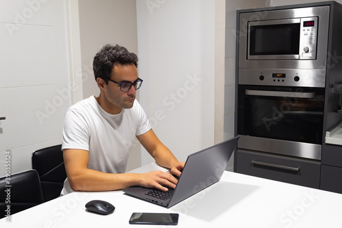 concentrated businessman working at home from kitchen with his laptop