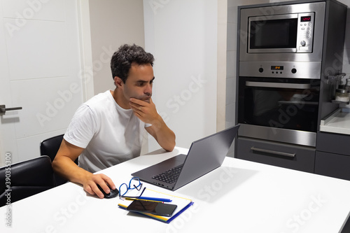 concentrated businessman working at home from kitchen with his laptop