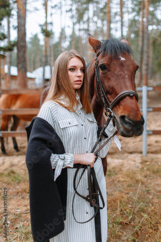 Girl rider standing next to the horse. The girl holds the horse's bridle