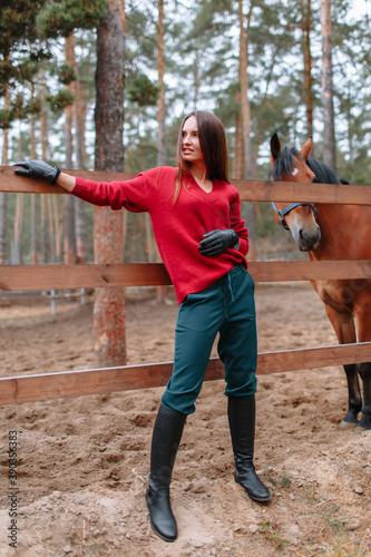 A girl standing next to a horse. Demonstration of clothing by a model © Alexey Tsibin