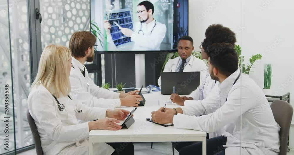 Close up of confident good-looking high-skilled mixed race male and female medical workers which having online conference in office room in hospital Close up of confident good-looking high-skilled mixed race male and female medical workers which having online conference in office room in hospital