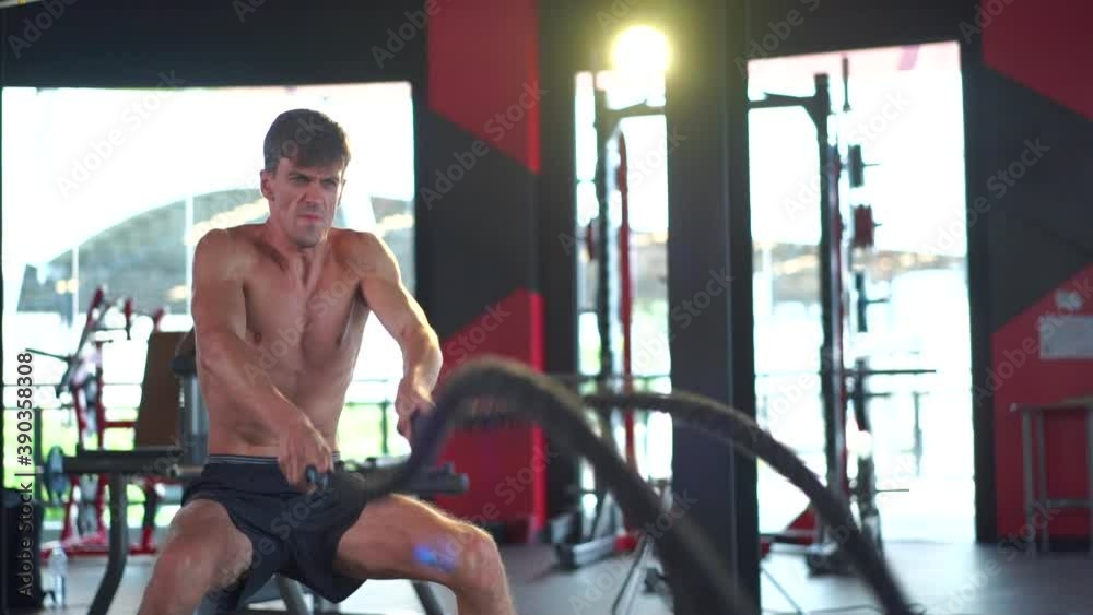 White caucasian man exercising with battle rope at gym White caucasian man exercising with battle rope at gym