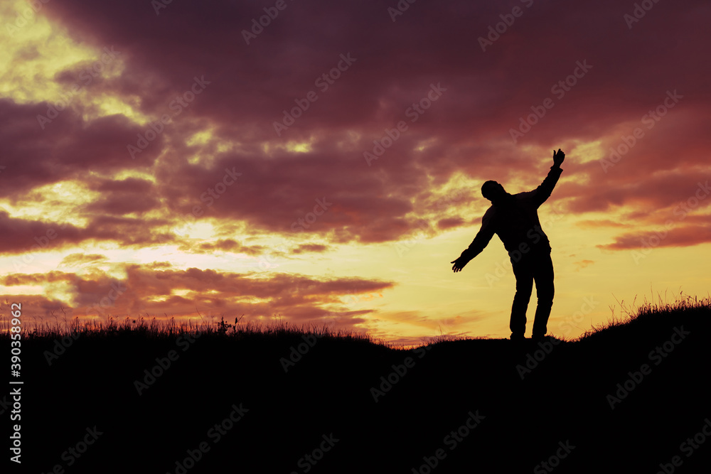 silhouette of a man who does not stand steadily and staggers against the sunset