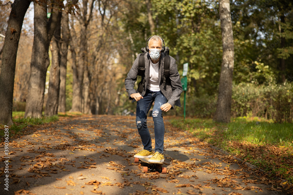 Happy mature man rolling skateboard in park Happy mature man rolling skateboard in park
